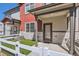 Inviting townhome exterior with a covered porch, stone accents, and manicured artificial lawn at 1353 Reynolds St # 2B, Fort Lupton, CO 80621