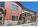 Modern townhome featuring a red exterior, stone accents, and a charming white picket fence at 1353 Reynolds St # 2B, Fort Lupton, CO 80621