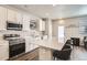 Modern kitchen featuring white cabinets, stainless steel appliances, and an island with bar stools at 1353 Reynolds St # 2B, Fort Lupton, CO 80621