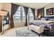 Main bedroom featuring three large windows, a queen-size bed, gray walls, and a comfortable sitting area at 9424 Ridgeline Blvd # I, Highlands Ranch, CO 80129