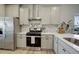 Well-equipped kitchen with stainless steel appliances, light-colored cabinets, and stone tile backsplash at 17761 E 95Th Pl, Commerce City, CO 80022