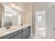 Double vanity bathroom with gray cabinets and a view into a bedroom at 5991 Sawdust Dr, Brighton, CO 80601