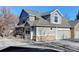 Two-story townhome with gray siding, stone accents, and a double car garage at 6397 Deframe Way, Arvada, CO 80004