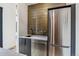 A bar area featuring a stainless steel refrigerator, stylish tile backsplash, and a sink with a black faucet at 200 Magnolia St, Denver, CO 80220