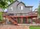 Exterior of home with backyard featuring a stone patio, artificial turf, and the home's red deck at 8838 S Dudley St, Littleton, CO 80128