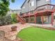 Backyard featuring a stone patio with artificial turf, a fire pit, and the home's red deck at 8838 S Dudley St, Littleton, CO 80128