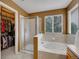 Bright bathroom featuring a glass-enclosed shower, soaking tub, and a walk-in closet at 8838 S Dudley St, Littleton, CO 80128