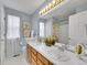 Bright bathroom featuring a double vanity, two windows, and a shower with patterned curtain at 8838 S Dudley St, Littleton, CO 80128