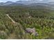 Stunning aerial shot showcases a home nestled in a lush forest, with winding roads leading to the property at 12653 Rancho Ct, Conifer, CO 80433
