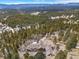 Expansive aerial view of a luxury home surrounded by a lush forest with mountain views at 12653 Rancho Ct, Conifer, CO 80433