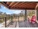 Beautiful deck space with cable railing that shows the wooded scenery and a relaxing red Adirondack chair at 12653 Rancho Ct, Conifer, CO 80433
