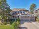 Stunning two-story home featuring a three-car garage, manicured lawn, mature trees and welcoming front porch at 9977 Falcon Creek Dr, Highlands Ranch, CO 80130