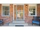 Charming brick porch with a secured wood door, sidelight window and seating, enhancing curb appeal at 9977 Falcon Creek Dr, Highlands Ranch, CO 80130