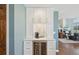 Custom built-in bar featuring beverage fridge, white cabinetry, and a marble backsplash at 9977 Falcon Creek Dr, Highlands Ranch, CO 80130