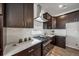 Modern kitchen featuring dark cabinets, stainless steel appliances, white subway tile backsplash, and quartz countertops at 5150 N Quemoy Ct, Aurora, CO 80019