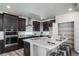 Modern kitchen boasts stainless appliances, dark cabinetry, spacious island with seating, and a convenient pantry at 5150 N Quemoy Ct, Aurora, CO 80019