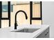 Close-up of a kitchen island featuring a stainless sink, modern faucet, and white countertops at 1601 Park Ave # 307, Denver, CO 80218