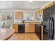 Eat-in kitchen showcasing black appliances, wood cabinets and large window to the backyard at 9683 Josephine Pl, Thornton, CO 80229