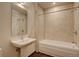 Elegant bathroom featuring a pedestal sink, tiled walls, and a bathtub with shower; modern and clean at 410 Acoma St # 212, Denver, CO 80204