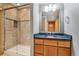 Bathroom with a glass-enclosed shower, granite countertop, and wooden vanity at 2626 Tamarac St, Denver, CO 80238