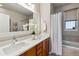 Bathroom featuring double sinks, a large mirror, and a shower-tub combination with a window at 2626 Tamarac St, Denver, CO 80238