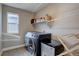 Functional laundry room features modern washer and dryer set, storage shelf, and a window for natural light at 15869 E Otero Ave, Centennial, CO 80112