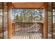 Covered balcony view with wooden floors and railings overlooking lush trees and a road at 67 Indigo Way, Castle Rock, CO 80108