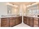 Double vanity in bathroom with marble countertop, wood cabinets, and framed mirrors at 15705 Red Deer Dr, Morrison, CO 80465