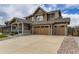 Inviting two-story home with a stone-accented porch and a wide driveway leading to a three-car garage at 15705 Red Deer Dr, Morrison, CO 80465