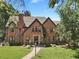 Stately brick Tudor home featuring a lush front lawn, manicured landscaping, and elegant architectural details at 6330 Montview Blvd, Denver, CO 80207