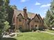 Brick Tudor home with manicured lawn, showcasing its architectural design and outdoor seating area at 6330 Montview Blvd, Denver, CO 80207