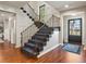 Elegant foyer with a staircase featuring iron railings, hardwood floors, and a stylish front door at 6330 Montview Blvd, Denver, CO 80207