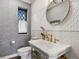 Chic powder room with white textured tile, brass fixtures, decorative mirror and a modern sink console at 6330 Montview Blvd, Denver, CO 80207