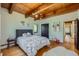 Charming bedroom with wood beam ceilings, playful artwork, a comfortable bed, and hardwood floors at 1559 Apex Rd, Franktown, CO 80116