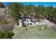 Aerial view of modern home with black trim, lawn, stone features, and treed background at 1559 Apex Rd, Franktown, CO 80116