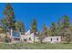 Striking modern home with flat roof design, surrounded by mature pine trees on a lush green lot at 1559 Apex Rd, Franktown, CO 80116