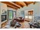 Inviting living room featuring terra cotta tile floors, a fireplace, wood beam ceilings, and leather sofa at 1559 Apex Rd, Franktown, CO 80116