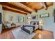 Cozy bedroom featuring wood beams, a decorative rug, and a comfortable seating area, offering a relaxing retreat at 1559 Apex Rd, Franktown, CO 80116