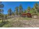 Small wooden outbuilding with a fenced yard in a wooded, grassy area at 1559 Apex Rd, Franktown, CO 80116