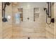 Luxurious walk-in shower with travertine tile, dual shower heads, and built-in niches for storage at 1559 Apex Rd, Franktown, CO 80116