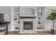 Cozy living room featuring a stone fireplace with built-in shelving and hardwood floors at 10345 Lions Heart, Lone Tree, CO 80124