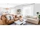 Bright living room with large windows, leather sofa, and decorative pillows with views into the adjacent kitchen at 9542 Cherry St, Thornton, CO 80229