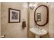 Charming powder room featuring a pedestal sink, decorative mirror, and stylish lighting at 13 Tamarade Dr, Littleton, CO 80127