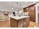 Spacious kitchen featuring a center island, dark wood cabinets, and hardwood floors that flow into an adjacent living room at 4220 S Yarrow Ct, Lakewood, CO 80235