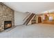 Cozy living room featuring a stone fireplace, open staircase, and view into the adjacent kitchen area at 7474 E Arkansas Ave # 17-07, Denver, CO 80231