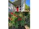 Charming home featuring a vibrant red door, complemented by a lush garden bursting with red and orange flowers at 742 Mockingbird Ln, Brighton, CO 80601