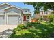 Charming home with a well-manicured front yard, colorful flowers, and a red front door at 742 Mockingbird Ln, Brighton, CO 80601