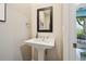 Elegant powder room featuring a pedestal sink with modern fixtures and a decorative framed mirror at 742 Mockingbird Ln, Brighton, CO 80601