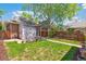 A home's backyard featuring lush green grass, a stone patio, a pergola, and mature trees at 2738 W 38Th Ave, Denver, CO 80211