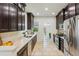 Galley kitchen with stainless steel appliances, dark wood cabinets, and stone tile flooring at 2738 W 38Th Ave, Denver, CO 80211
